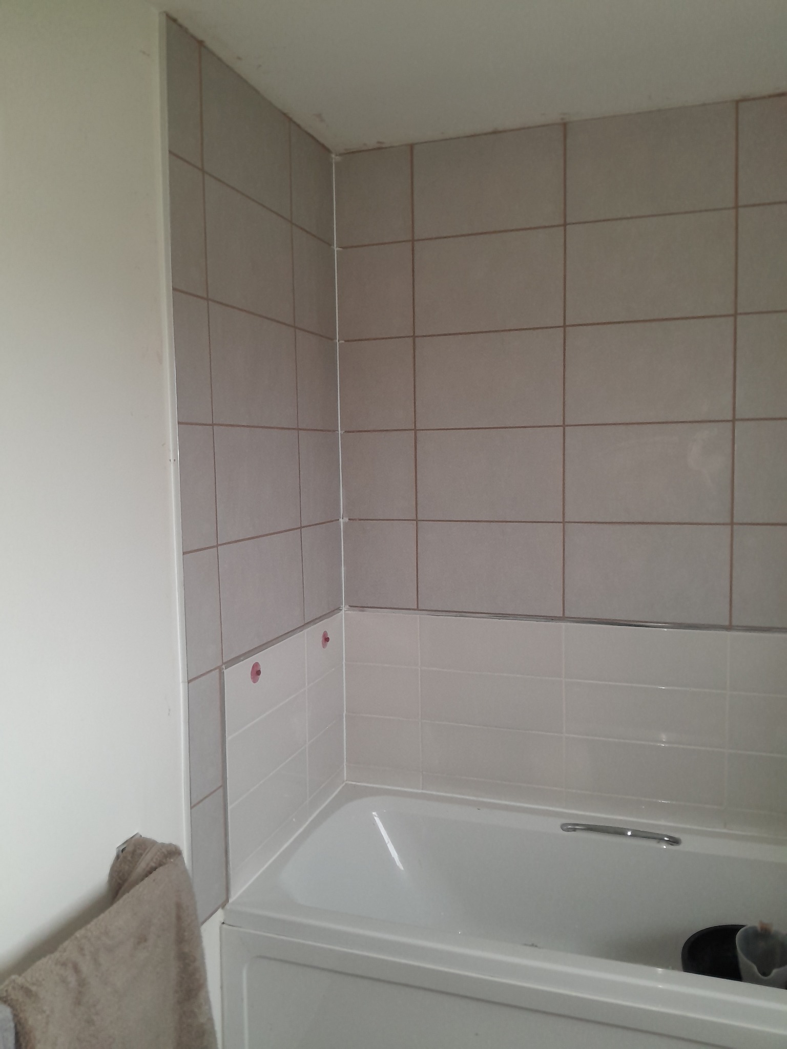 Completed bathroom wall tiling around bath in Bathgate by Herringbone of Lanark