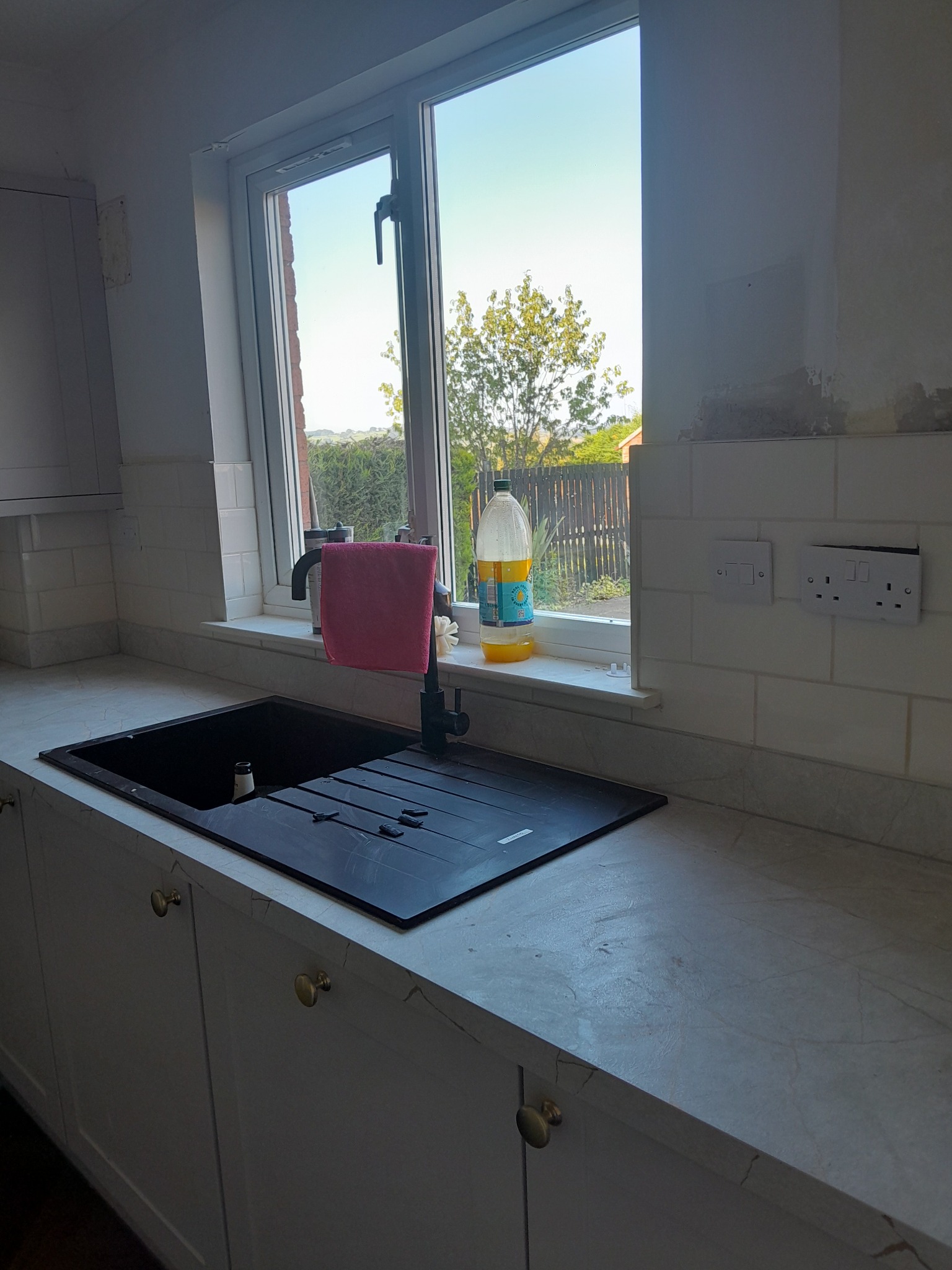 Finished white tiled splashback around kitchen sink and window